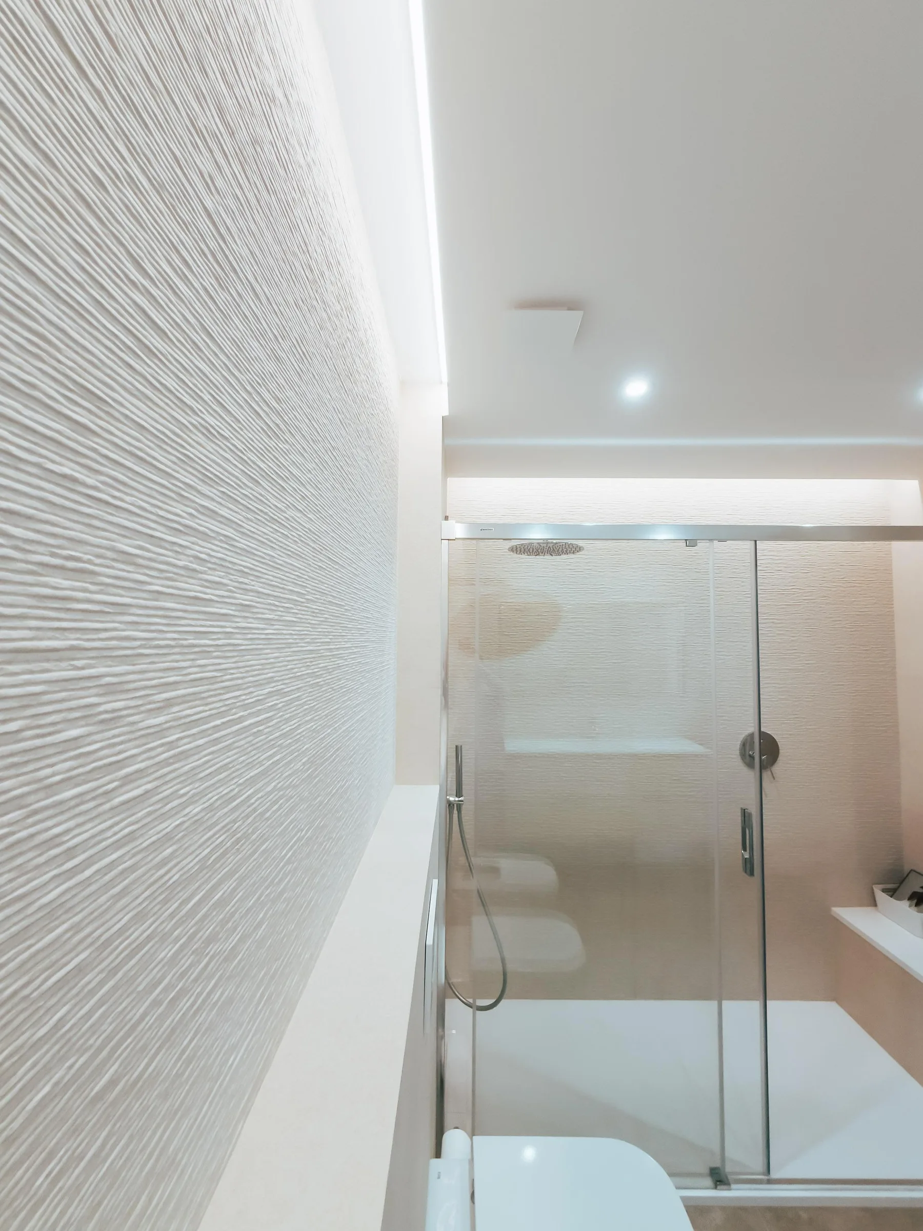 Baño reformado con ducha a ras y revestimiento texturizado de Suiteak